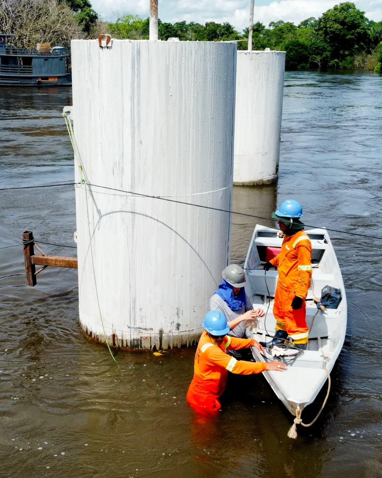 Technical team and instrumentation next to piles in an Amazon river environment